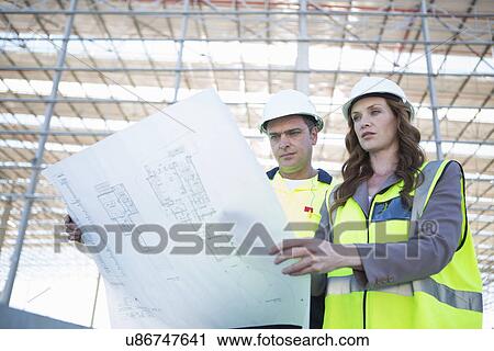 Site manager and architect looking down at blueprint on construction site View Large Photo Image Stock Image - Site manager and architect looking down at blueprint on construction site. Fotosearch