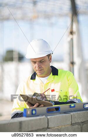 Stock Image - Site manager checking spirit level on construction site wall. Fotosearch