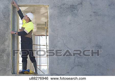 Stock Photograph - Site manager reaching to check doorway on construction site. Fotosearch