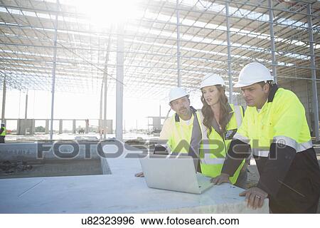Site managers and architect looking at laptop on construction site View Large Photo Image Stock Photograph - Site managers and architect looking at laptop on construction site. Fotosearch