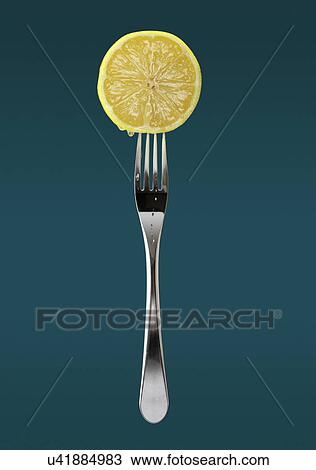 Stock Image - Still life of fresh slice of lemon on fork. Fotosearch