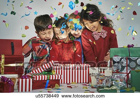 Surprised brothers and sisters unwrapping glowing christmas gift box with exploding confetti View Large Photo Image Stock Photo - Surprised brothers and sisters unwrapping glowing christmas gift box with exploding confetti. Fotosearch
