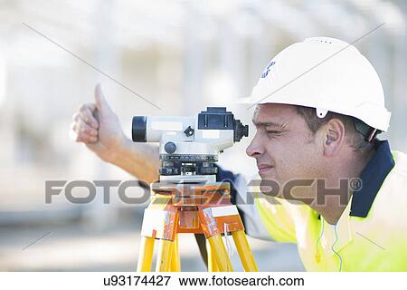 Surveyor looking through level on construction site View Large Photo Image Stock Photo - Surveyor looking through level on construction site. Fotosearch