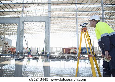 Stock Photography - Surveyor using tripod and level on construction site. Fotosearch