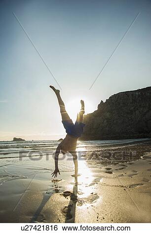 Stock Photograph - Teenage boy doing handstand at beach, Camaret-sur-mer, Brittany, France. Fotosearch