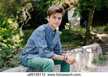 Teenage boy sitting on stone wall, portrait View Large Photo Image Stock Image - Teenage boy sitting on stone wall, portrait. Fotosearch