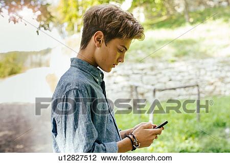 Teenage boy using cell phone View Large Photo Image Stock Image - Teenage boy using cell phone. Fotosearch