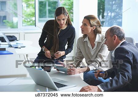 Three businessmen and women having informal meeting in office View Large Photo Image Stock Photography - Three businessmen and women having informal meeting in office. Fotosearch