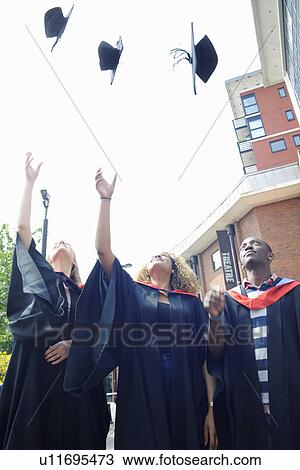 Three college students throwing graduation caps mid air View Large Photo Image Stock Image - Three college students throwing graduation caps mid air. Fotosearch