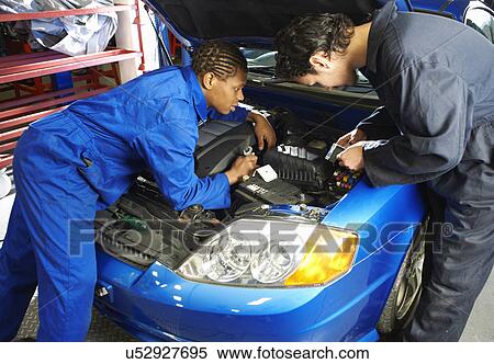 Stock Photography - Two college students looking at car engine in garage workshop. Fotosearch