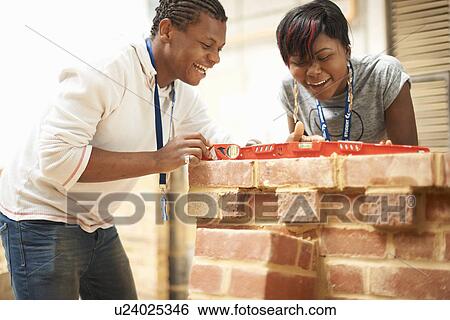 Two college students using spirit level in bricklaying workshop View Large Photo Image Stock Photograph - Two college students using spirit level in bricklaying workshop. Fotosearch