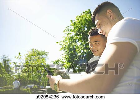 Stock Photograph - Two young adult friends looking at text message on smartphone. Fotosearch