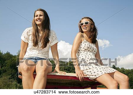 Picture - Two young women sitting in trailer. Fotosearch