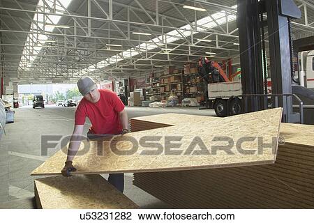 Warehouse worker lifting wooden boards in hardware store warehouse View Large Photo Image Stock Image - Warehouse worker lifting wooden boards in hardware store warehouse. Fotosearch