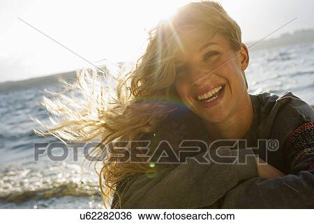 Stock Photograph - Woman all wrapped up on windy beach. Fotosearch