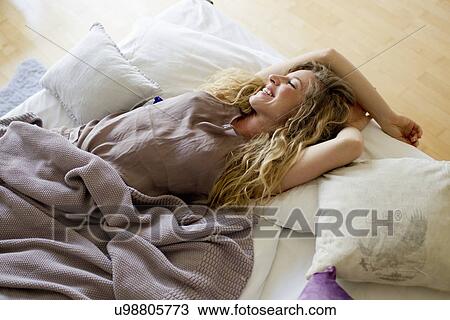 Stock Image - Woman lying in bed day-dreaming. Fotosearch