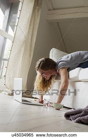 Woman lying on sofa using laptop View Large Photo Image Stock Photography - Woman lying on sofa using laptop. Fotosearch
