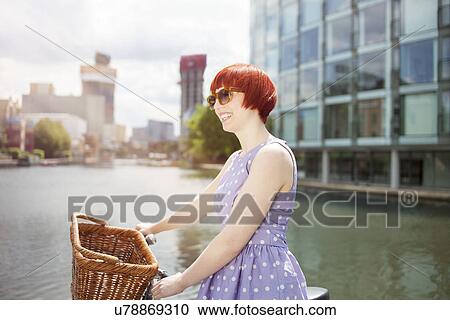 Stock Image - Woman pushing bike along canal, East London, UK. Fotosearch