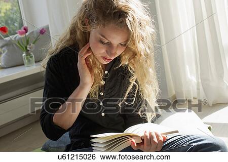 Stock Photograph - Woman sitting on floor reading. Fotosearch