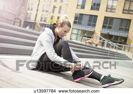 Woman sitting on ground tying shoe laces View Large Photo Image Picture - Woman sitting on ground tying shoe laces. Fotosearch