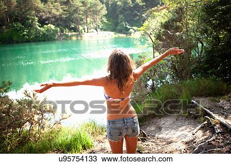 Stock Image - Woman stretching by the Blue Pool, Wareham, Dorset, United Kingdom. Fotosearch