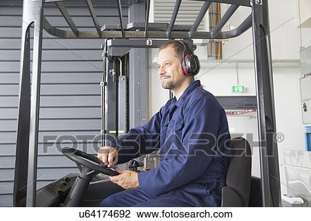 Stock Image - Worker in forklift truck in industrial plant. Fotosearch