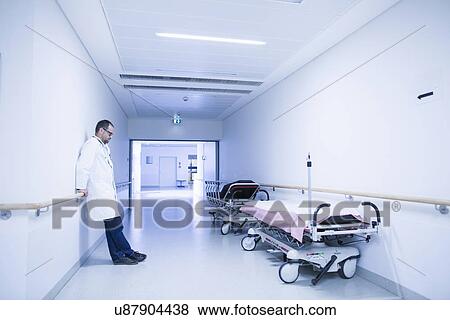 Stock Photo - Worried doctor with head down in hospital corridor. Fotosearch
