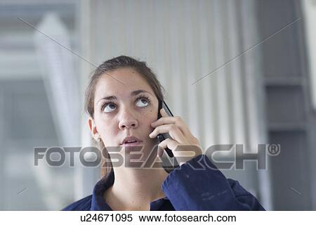 Worried female engineer talking on smartphone in factory View Large Photo Image Stock Photography - Worried female engineer talking on smartphone in factory. Fotosearch