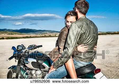 Young couple straddling motorcycle on arid plain, Cagliari, Sardinia, Italy View Large Photo Image Stock Photograph - Young couple straddling motorcycle on arid plain, Cagliari, Sardinia, Italy. Fotosearch