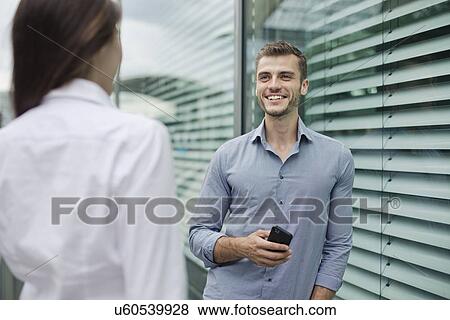 Young couple talking, man holding cell phone View Large Photo Image Stock Photo - Young couple talking, man holding cell phone. Fotosearch