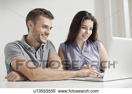 Stock Image - Young couple using laptop. Fotosearch