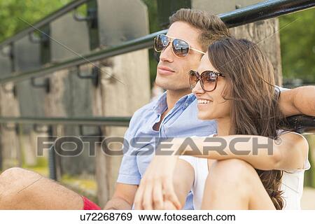 Young couple wearing sunglasses, smiling View Large Photo Image Stock Photo - Young couple wearing sunglasses, smiling. Fotosearch