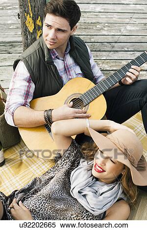 Young couple with acoustic guitar reclining on pier View Large Photo Image Stock Photography - Young couple with acoustic guitar reclining on pier. Fotosearch