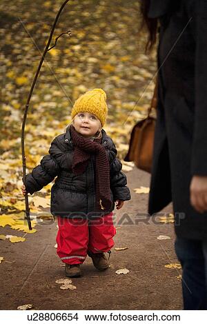 Young girl on walk wearing winter clothes, holding stick View Large Photo Image Picture - Young girl on walk wearing winter clothes, holding stick. Fotosearch