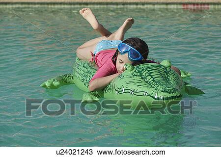 Stock Image - Young girl relaxing on inflatable in swimming pool. Fotosearch