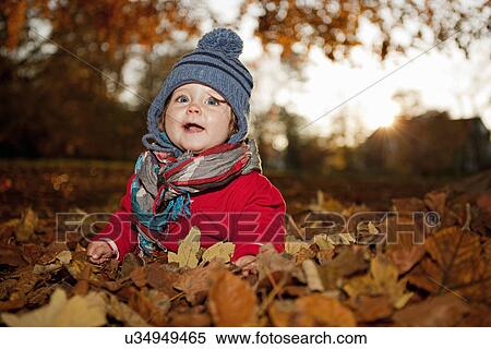 Stock Photography - Young girl sitting in autumn leaves. Fotosearch