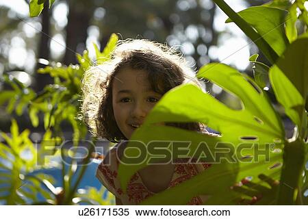 Young girl, smiling, standing amongst foliage View Large Photo Image Stock Photography - Young girl, smiling, standing amongst foliage. Fotosearch