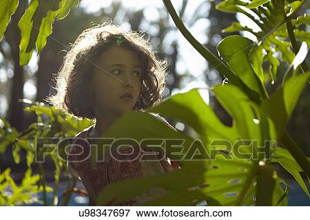 Young girl, worried expression, standing amongst foliage View Large Photo Image Stock Photo - Young girl, worried expression, standing amongst foliage. Fotosearch