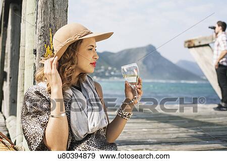 Young glamorous woman drinking wine on coastal pier, Cape Town, Western Cape, South Africa View Large Photo Image Stock Photo - Young glamorous woman drinking wine on coastal pier, Cape Town, Western Cape, South Africa. Fotosearch