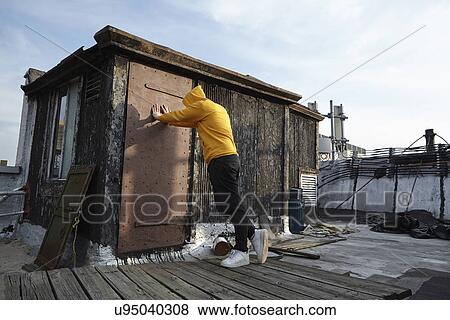 Young man leaning against rooftop hut and looking down View Large Photo Image Stock Photo - Young man leaning against rooftop hut and looking down. Fotosearch