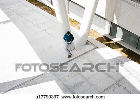 Stock Photo - Young man reading newspaper, high angle. Fotosearch
