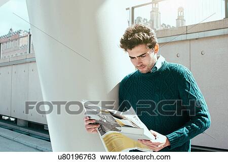 Stock Image - Young man reading newspaper. Fotosearch