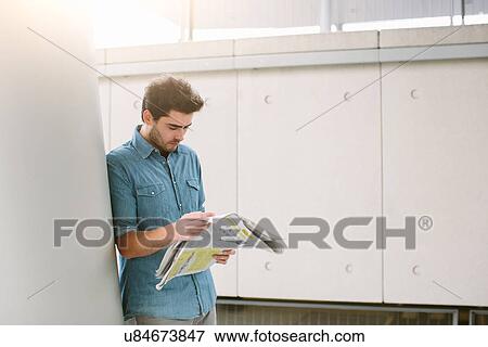 Stock Photo - Young man reading newspaper. Fotosearch