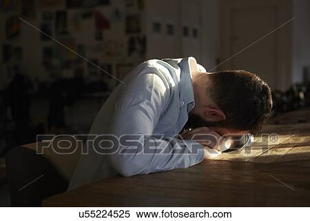 Young man sitting at kitchen table with his head down View Large Photo Image Stock Photography - Young man sitting at kitchen table with his head down. Fotosearch