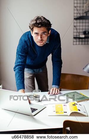 Stock Photo - Young man using laptop at desk. Fotosearch