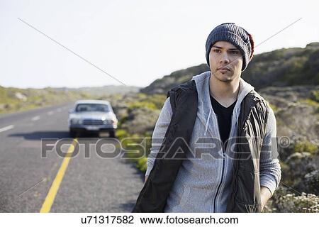 Stock Image - Young man walking along road, Cape Town, Western Cape, South Africa. Fotosearch
