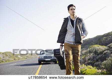 Young man walking along road with guitar case, Cape Town, Western Cape, South Africa View Large Photo Image Picture - Young man walking along road with guitar case, Cape Town, Western Cape, South Africa. Fotosearch