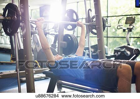 Picture - Young man weight lifting with barbell. Fotosearch