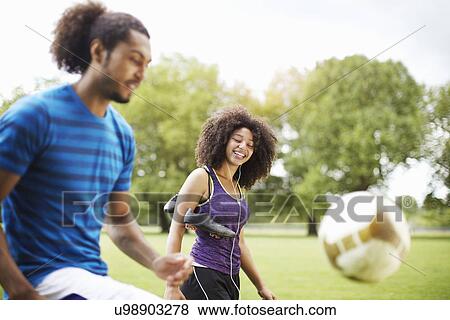 Stock Photo - Young soccer couple playing keepy uppy in park. Fotosearch