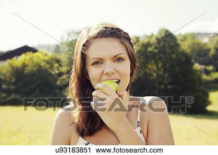 Stock Image - Young woman biting apple. Fotosearch